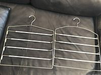 Two identical four-tier metal closet racks laid on black surface, showing overall design and condition