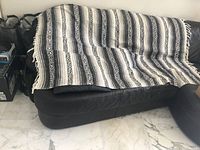 Striped acrylic blanket draped over sofa showing pattern and fringe