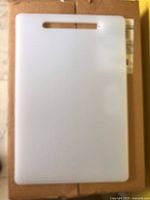 Front view of rectangular white plastic cutting board placed on a box