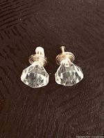 Two clear crystal-style knobs with screw stems displayed on dark surface