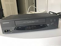 Front view of Daewoo VCR showing brand, 4-head high speed rewind marking, tape slot, control buttons and AV input