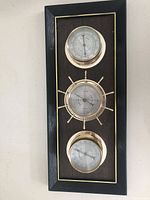 Front view showing three brass instruments on wood plaque