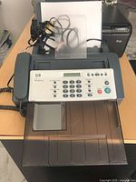 Front view of HP 640 fax machine showing handset, control panel, trays and cords