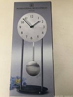 Front of retail box showing design of metal pendulum clock