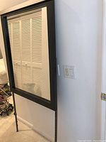 Full view of rectangular mirror with dark frame and two supports, one taped