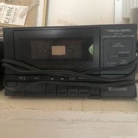 Front view of Realistic SCP-32 cassette player showing cassette window, controls, and attached cable