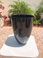 Front view of glossy black planter on table outdoors