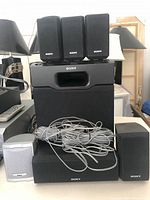 Front view showing Sony subwoofer, center speaker, five Sony satellites, one RCA satellite, and wiring