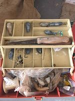 Open tackle box showing tray with sinkers, knife, hooks, line and lures