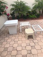One image showing white end table, white PVC footstool, cream plastic step stool, white metal mesh footrest