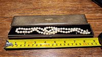 Single strand pearl necklace displayed in open brown Jubilee Jewellers branded box, measuring tape placed beneath showing approximately 20 inches in length.