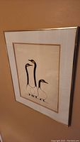 Full view of framed artwork showing three stylized geese in black and gold on beige background