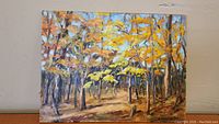 Full view of oil painting depicting late fall forest scene with vibrant autumn colors in trees and ground, signed by artist.