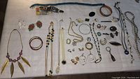 Photo showing the entire assortment of vintage jewelry including necklaces, bracelets, earrings, rings, and brooches arranged on a cloth surface.