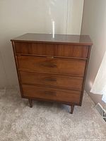 Front view of the 4 drawer dresser showing the wood grain finish and metal handles on each drawer.