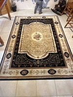 Full view of the rectangular carpet laid out on a tiled floor, showing its detailed floral and ornamental patterns and color palette.
