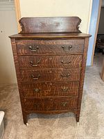 Frontal view of oak dresser showing five drawers, carved backsplash, and drop-handle hardware.