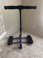 Front view of the blue Leg Master exercise equipment showing padded handlebar, vertical bar with logo, and dual foot pedals.