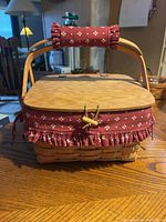 Front view of the Longaberger basket showing woven body, red fabric liner with ruffles and wooden lid with handle.