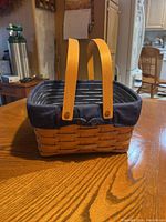 Front view of woven basket showing rectangular shape, two wooden handles, and fabric liner inside.