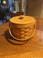 Photo showing the exterior view of the round woven Longaberger basket with natural wood finish and wooden lid with knob.