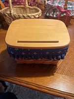 Top view of the Longaberger basket showing the wooden lid and blue fabric liner with white floral patterns.