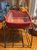 View of rectangular wooden basket on standing metal holder with decorative detail and fabric-lined compartment insert