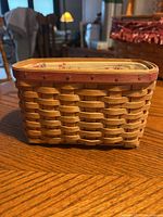 Front view of rectangular woven Longaberger basket showing natural wood color and reddish wooden rim.