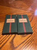 Two Longaberger green boxes with red and gold branding on a wooden surface.