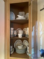 Cabinet with stacked plates, cups, bowls, and platters showing floral patterned Pfaltzgraff china