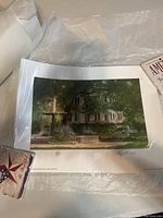 Photo of the full print showing a house and garden scene with a fountain in front, the print is laid on white tissue paper for protection.
