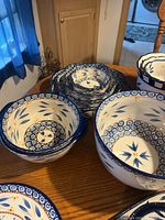 Multiple sizes of blue and white patterned ceramic bowls and plates arranged on table