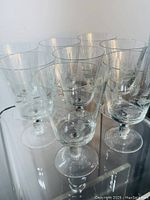 Eight clear crystal wine glasses arranged closely, showing etched designs in the bowl and faceted stems.