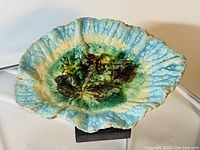 Top side view of antique ceramic dish shaped like a begonia leaf with turquoise and green majolica glaze.