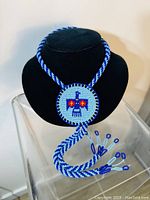 Full view of the beaded Thunderbird medallion necklace showing the round medallion and braided beaded rope with tassels.