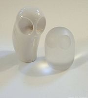 Two owl figurines: larger white porcelain Royal Dux owl and smaller frosted glass owl together on white surface