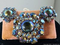 Front view of Sherman brooch with matching earrings mounted on orange fabric, showing rhinestone colors and design.