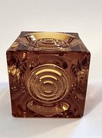 Front view of the amber glass votive holder showing the bull's eye circular pattern