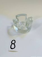 Front view of clear Wiesenthal Hutte art glass votive candle holder, showing its segmented curved rim and solid base.
