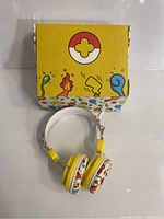 Photo of children's headphones and packaging box with colorful cartoon design on white background.