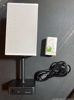 Black desk lamp with fabric shade, USB charging ports on base, LED bulb in box, power cord coiled beside lamp.