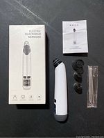 Photo showing the electric blackhead remover with its box, user manual, four suction heads, and six metal extraction tools.