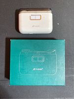 White electric nail clipper device by FUEND with teal box underneath on black background.