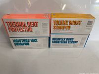 Four boxed hair care products arranged in two stacks showing product names and branding.