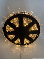 Top view of the black spool wound with warm white LED fairy lights glowing softly.