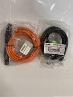Two male to female XLR cables, one orange and one black, sealed in plastic packaging with labels showing model numbers and barcodes.