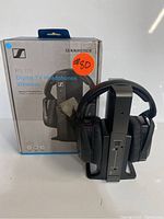 Photo of Sennheiser RS 175 headphones on their base station with original box in background, showing full set including packaging and headphones on stand.