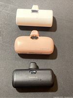 Top view showing white, pink, and black power banks with built-in Lightning connectors on black surface.