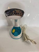 Front view of the portable clothing steamer showing chrome steam plate, power cord, and control button on the base.