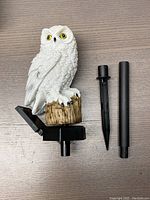 Photo showing one owl-shaped garden light figure separated from its parts on a wooden surface.